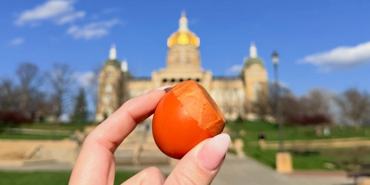 Hand holding a cascarón egg with the Iowa State Capitol blurred in the background