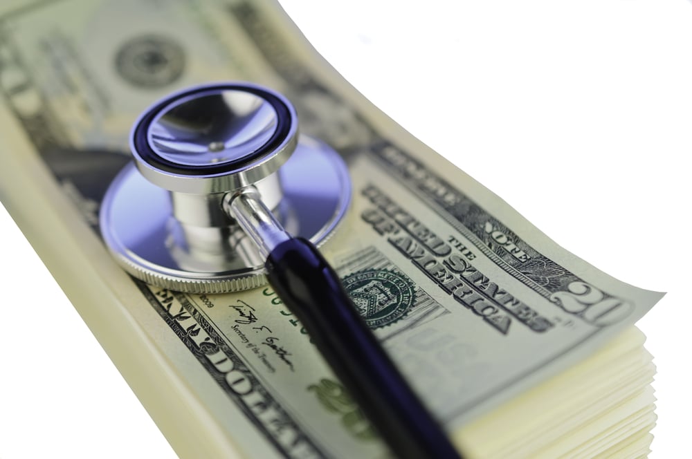 Stethoscope on stack of U.S. dollar bills representing healthcare costs and insurance expenses