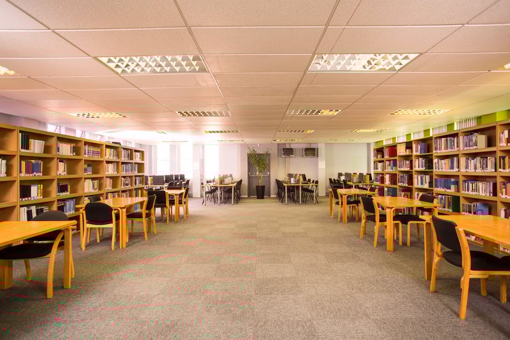 Empty library with tables and bookshelves on both sides. 